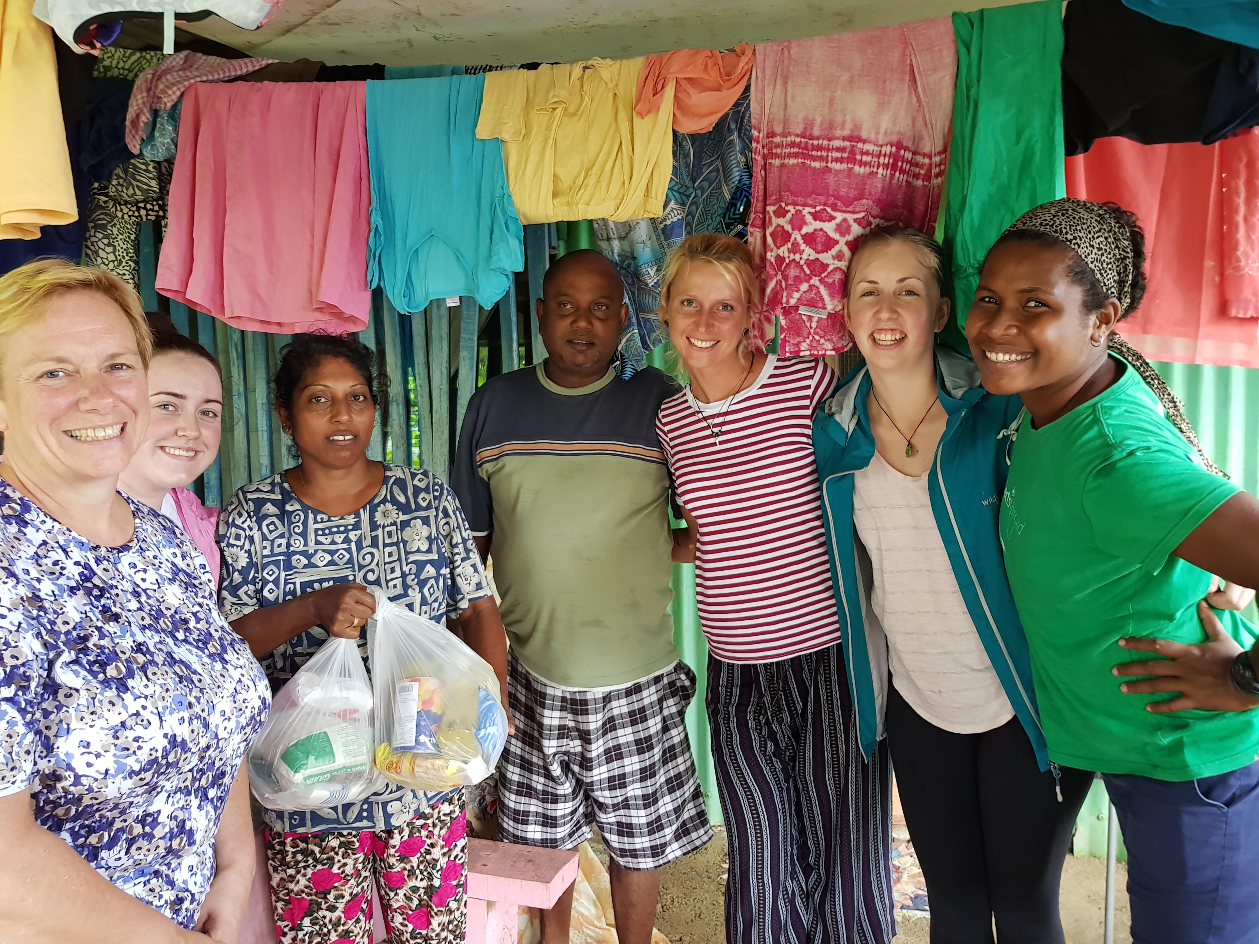 Female Projects Abroad Community Volunteers donate food to a local woman whose house was damaged by flooding in Fiji. Female Community Volunteers pose with a local couple at a Community Day during Cultural Immersion in Fiji.